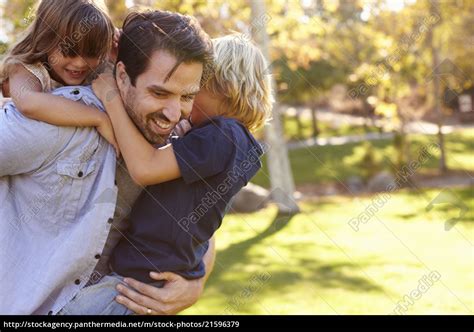 father carrying son and daughter as they play in park royalty free image 21596379