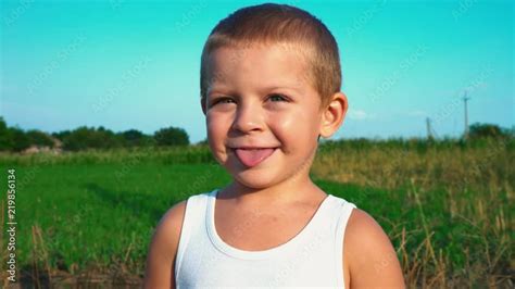 Vidéo Stock 4 Year Old Boy In A White T Shirt Smiles And Shows Tongue