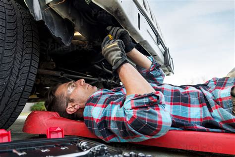 Car Mechanic Working Underneath The Front Of A Truck Stock Photo