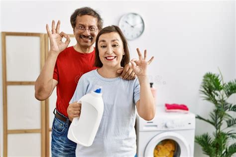 Middle Age Interracial Couple Doing Laundry Holding Detergent Bottle