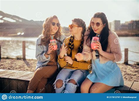 Three Girls Sit On The Beach Near The River Talk Gossip Joke Laugh Smile At Womans Day