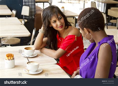 Two Beautiful Females Having Coffee Together In A Coffee Shop Stock