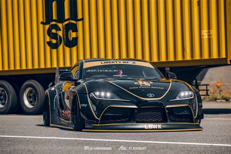 A Black And Yellow Sports Car Driving Down The Road Next To A Large