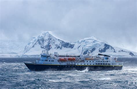 Ship Passing Snow Covered Mountains In Antarctica Stock Photo