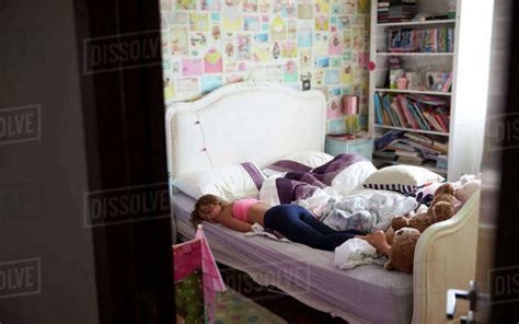 Close Up Of Tired Young Girl Sleeping On Bed In Bedroom Stock Photo