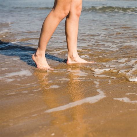 Крупный план босых ног женщины на пляже Бесплатно Фото