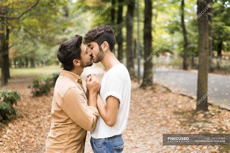 Young Gay Couple Holding Hands And Kissing In Autumnal Park — Leisure Relationship Stock