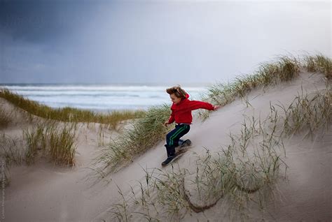 Jumping Down A Sand Dune On A Windy Day Del Colaborador De Stocksy