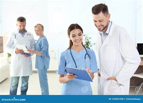 Doctor And Medical Assistant With Colleagues In Clinic Stock Photo