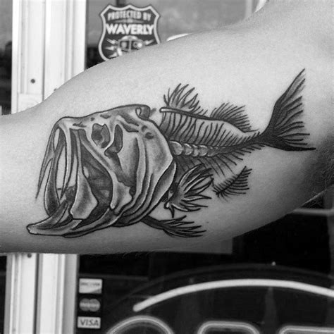 Experiment with tribal design the next time you get a skull tattoo. Black And Grey Guys Inner Arm Skeleton Of Fish Tattoo