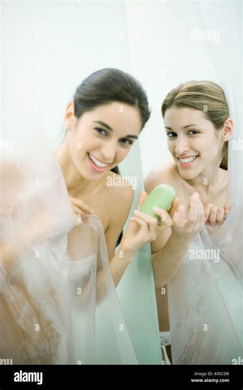 Two Young Women Taking Showers One Handing The Other A Bar Of Soap