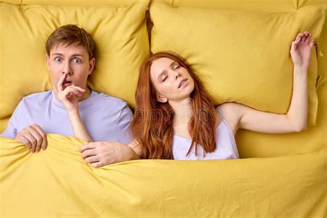 Sleeping Problems And People Concept Unhappy Man Lying In Bed With Redhead Woman Disturbing