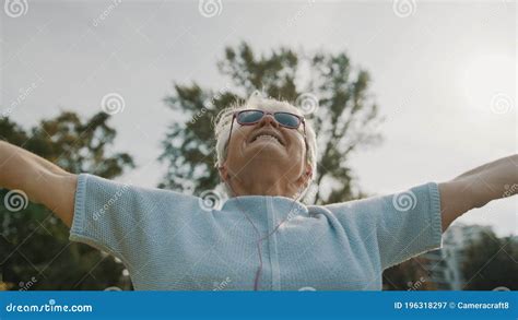 Cool Grandmother With Pink Sunglasses And Headphones Stretching In The