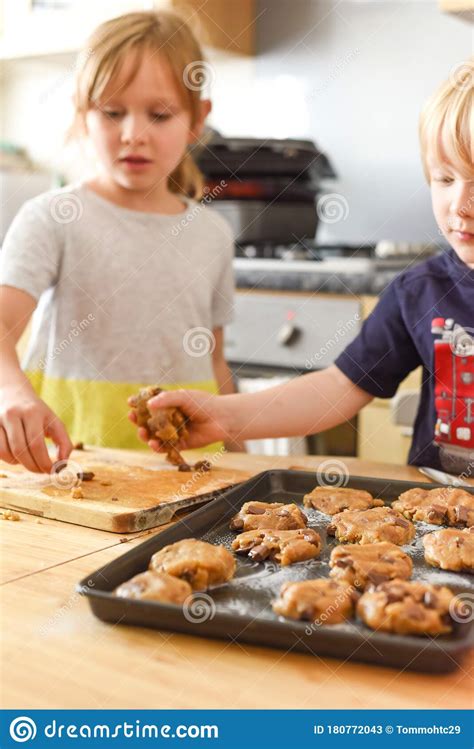 Kids Making Cookies In Kitchen Placing Dough On Tray For Cooking At