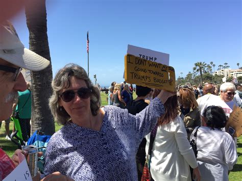 A Woman Holding Up A Sign In Front Of A Group Of People On The Grass