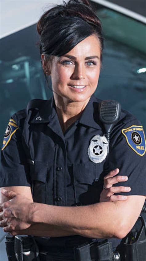 A Woman Police Officer Standing In Front Of A Car With Her Arms Crossed