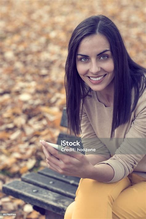 Tersenyum Wanita Cantik Muda Duduk Di Bangku Di Taman Dan Sms Foto Stok Unduh Gambar Sekarang