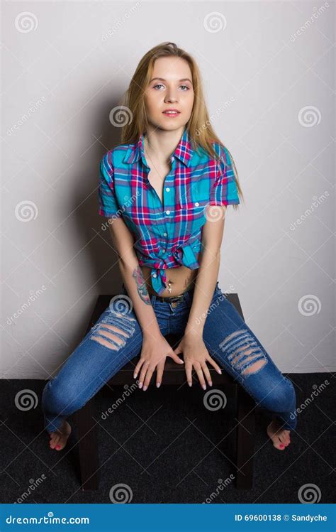 Sexy Junges Mädchen In Den Jeans Und Ein Kariertes Hemd Welches Das Sitzen Auf Dem Couchtisch