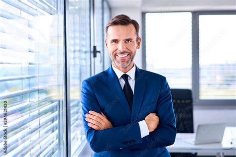 Portrait Of Successful Businessman Standing In Corner Office Stock