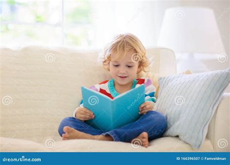 Child Reading Magazine On Sofa Stock Photography