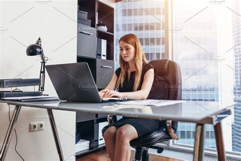 Woman Working On Laptop Sitting At Her Desk In Office Woman Office Business Women Boss Lady Desk
