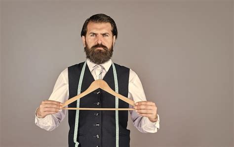 premium photo tailor man holds in his hand a hanger handsome man in formal vest wardrobe for