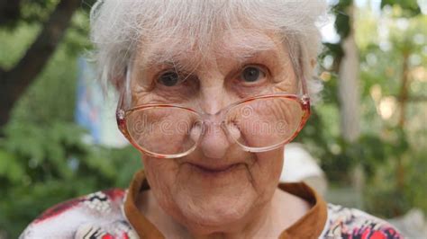 Old Woman In Eyeglasses Looking Into Camera And Smiling Outdoor Portrait Of Happy Granny In