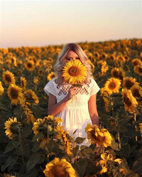 A Woman Standing In The Middle Of A Sunflower Field Holding A Large