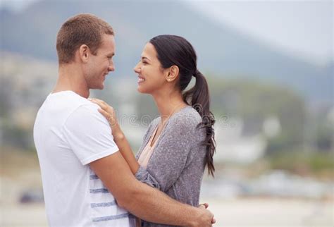 Sharing A Loving Gaze And A Warm Embrace An Affectionate Young Couple At The Beach Stock Image
