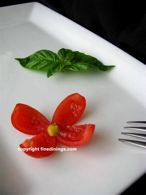 A White Plate Topped With Slices Of Tomato And A Green Leaf On Top Of It