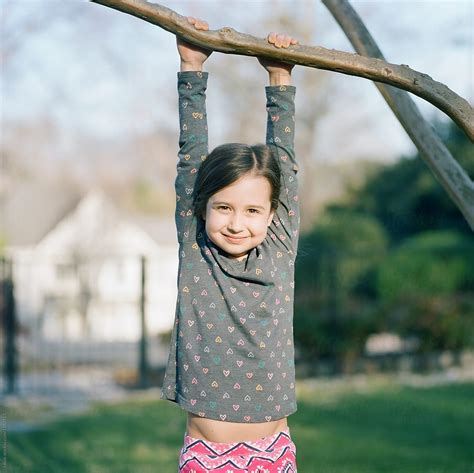 Cute Young Girl Hanging On A Tree Branch By Stocksy Contributor
