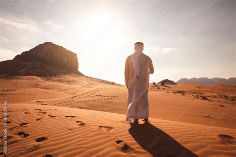 Arab Man Stands Alone In The Desert And Watching The Sunset Stock