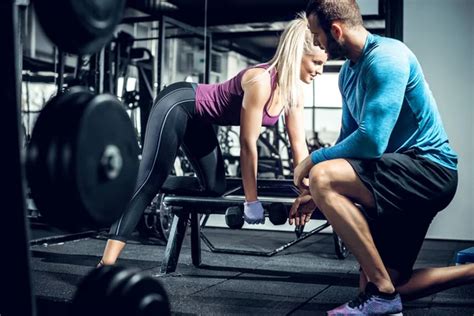 Personal Trainer Helps His Client During Row Exercise Stock Image