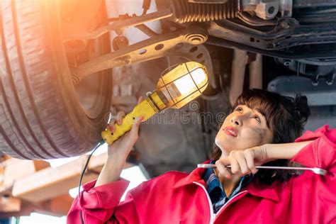 Woman Mechanic Examining Under The Car At The Repair Garage Stock Photo