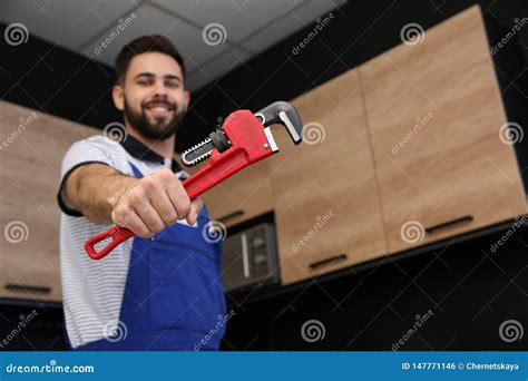 Male Plumber Holding Pipe Wrench In Kitchen Repair Service Stock Photo