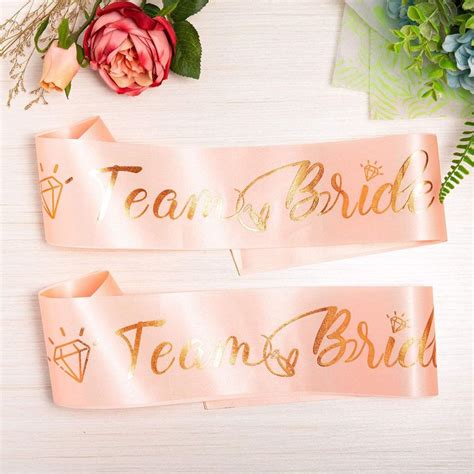 Two Pink Sashes With Gold Foil Lettering On Them One Says Team Bride And The Other Says Team Bride