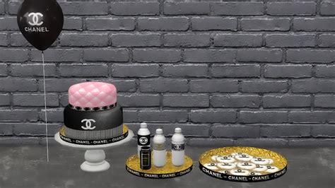 Three Tiered Cake With Chanel Decorations On It And Two Small Round
