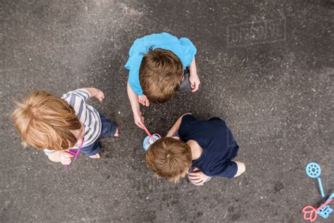 Looking Down On Three Boys Playing Outside With Bubbles Stock Photo