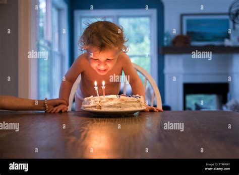 Candlelit Toddler Boy Blowing Out Candles On Birthday Cake Stock Photo