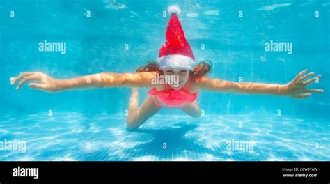 Happy Girl Dive And Swim Underwater Wearing Santa Claus Hat In The Pool