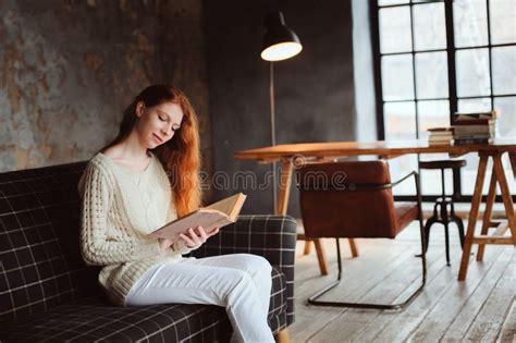 Young Beautiful Redhead Woman Relaxing At Home In The Autumn Cozy Evening And Reading Book Stock