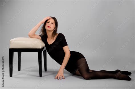 Woman In Black Leotard And Tights Leaning Against Footstool Stock Photo