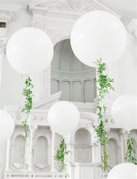 White Balloons And Greenery Are Hanging From The Ceiling In Front Of An