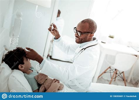 Positive Delighted Doctor Treating Ill Little Patient Stock Image