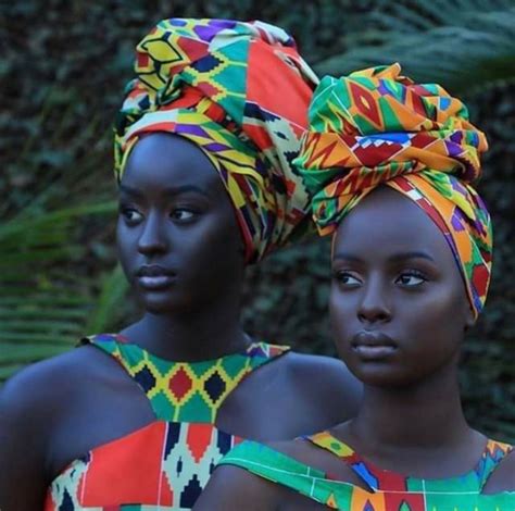 Two African Women Wearing Head Wraps And Colorful Dresses In Front Of