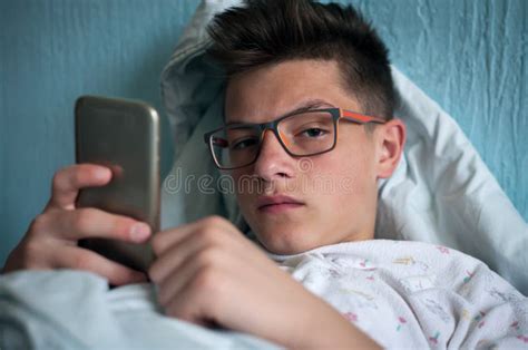Tiener Die In Bed Liggen En Smartphone Gebruiken Stock Afbeelding