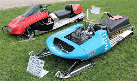 Three Different Types Of Snowmobiles Parked On The Grass In Front Of