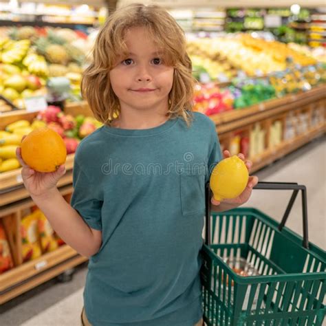 Child With Lemon And Orange Kid In A Food Store Or A Supermarket