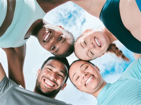 Portrait Of A Diverse Group Of Happy Sporty People From Below Joining Their Heads Together In A