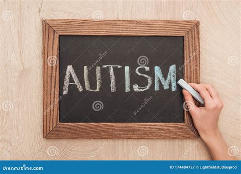 Partial View Of Woman Writing Autism Lettering With Chalk On Chalkboard
